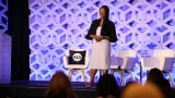 Lakisha Woods, AIA EVP/CEO, stands onstage in front of a purple geometric background at the 2024 Women's Leadership Summit in Chicago