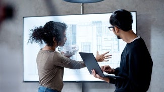 Man and woman working on a white screen