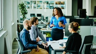 Colleagues working at a desk with woman in blue standing