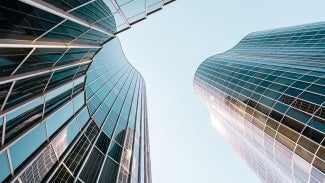 Looking up at sky through skyscraper with glass windows