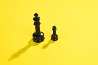 black king and pawn chess pieces on yellow background